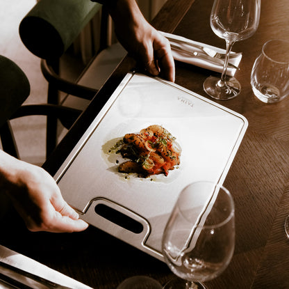 Dish of food on a cutting board with wine glasses