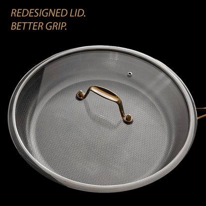A close up of a round cookware lid with a textured silver gray surface and a metallic gold handle, shown on a black background with the text 'REDESIGNED LID. BETTER GRIP.