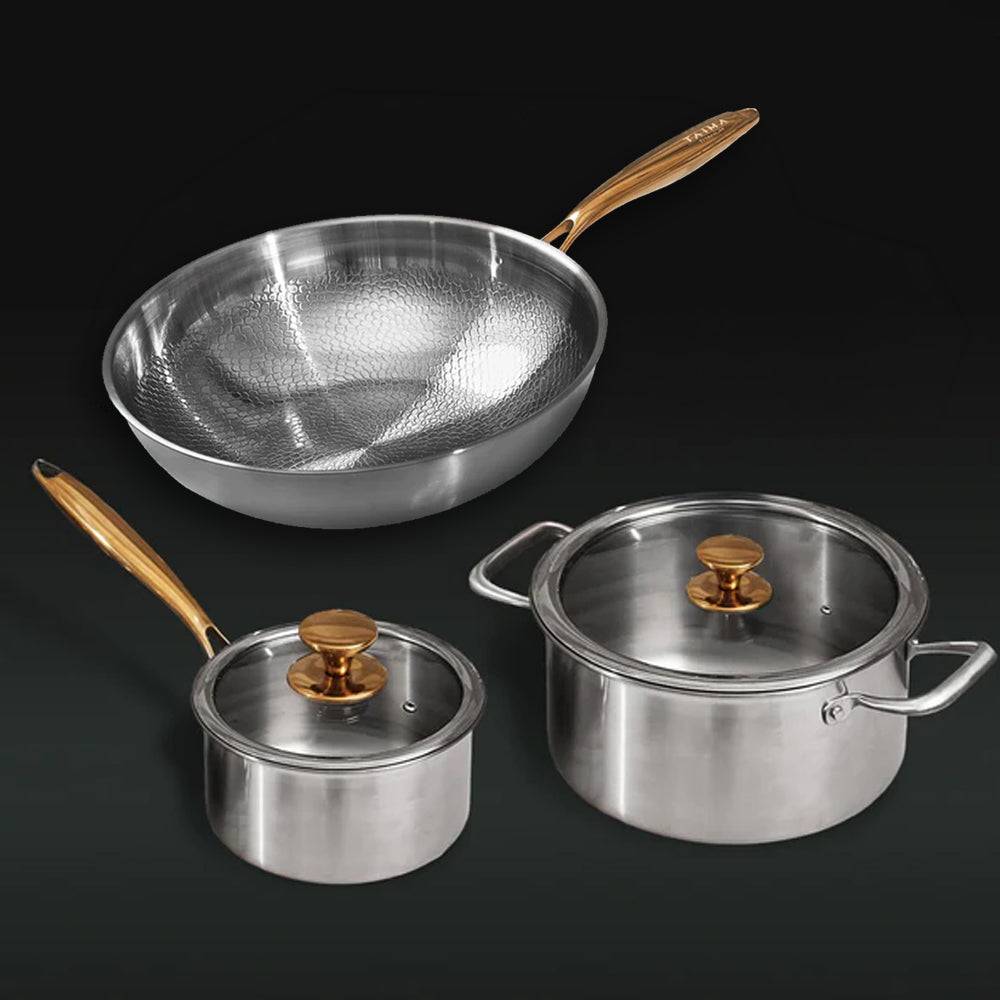 Set of titanium cookware with gold handles on a black background